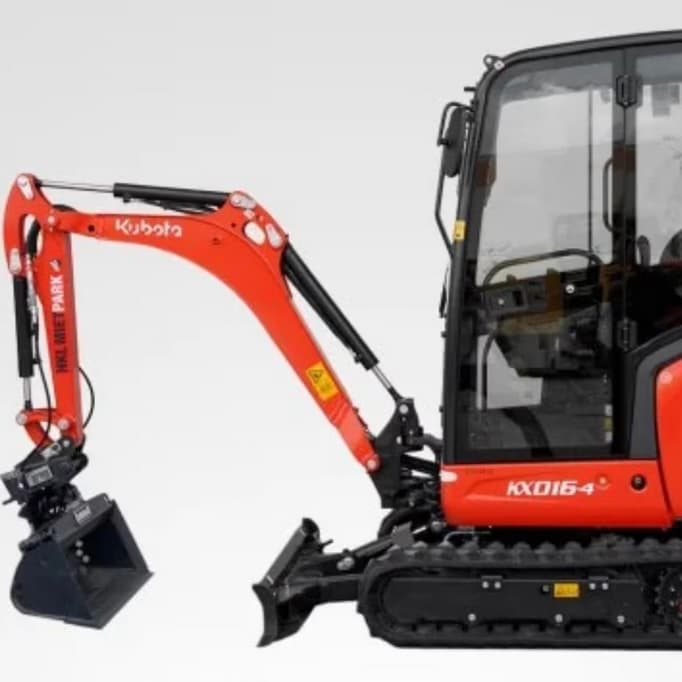 Oranger Bagger mit Fahrerkabine steht auf Betonboden.